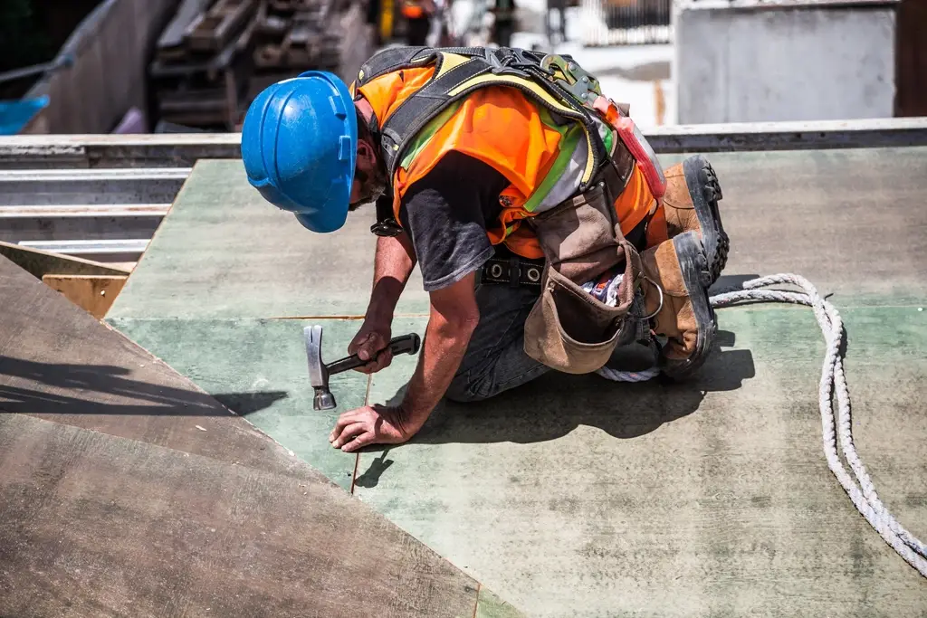 Roofing contractor in safety gear working on a roof